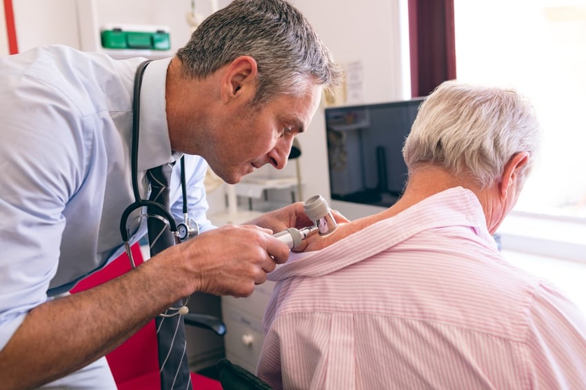 dermatologist performing a skin exam on an older patient
