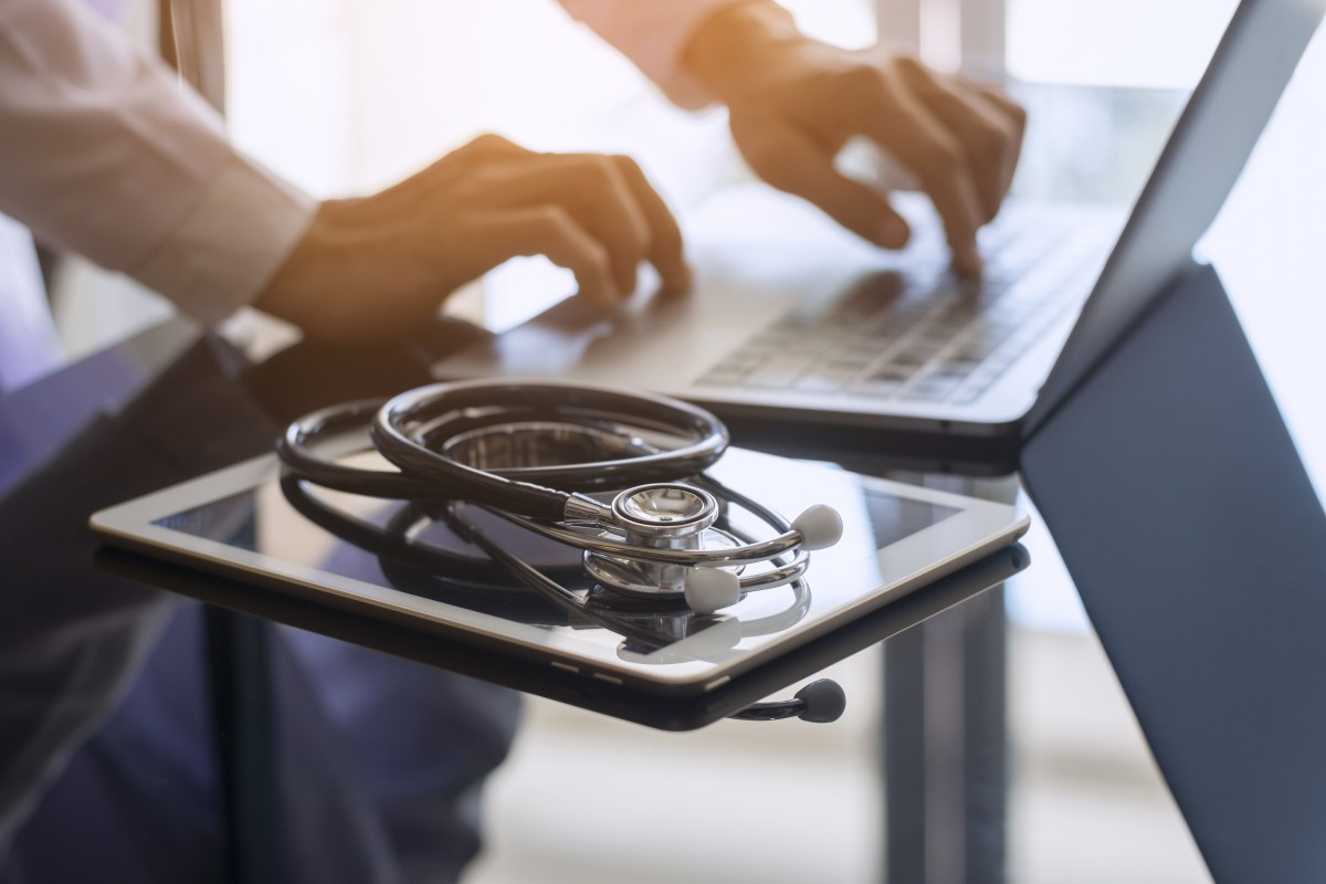 doctor updating electronic health records on laptop
